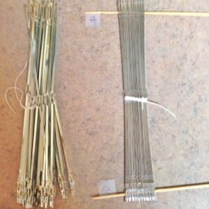 I found out, while threading, that I needed to redistribute heddles.  Ugh. I whittled bamboo skewers to hold them in place for the transfer.  The pieces of tape keep them from sliding off, and I write the number of heddles on the tape.