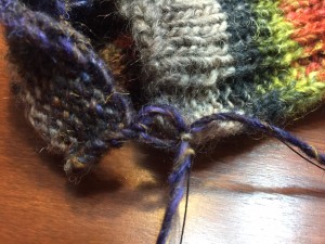 At the base of the seam, bring the yarn through one loop on the very edge, do the same on the other side, and come back into the first loop to create a circle.  When this is snugged, you will have an even edge with no notch at the seam!